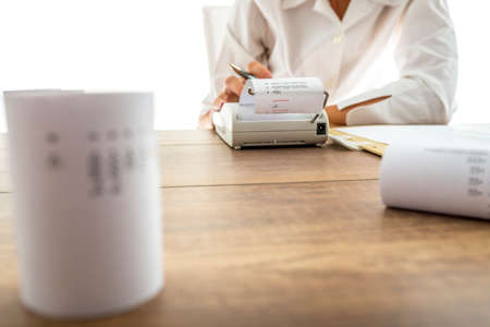 Business accountant or financial adviser making calculations using adding machine.
