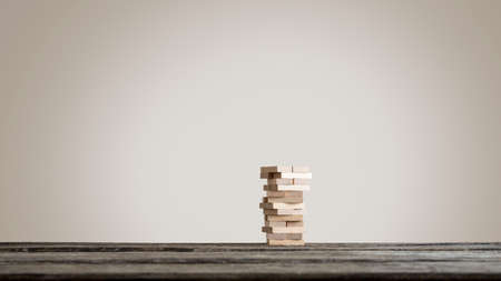 Tower or pile of wooden bricks with copyspace on table against blank brown wall. Horizontal copy spaceの写真素材