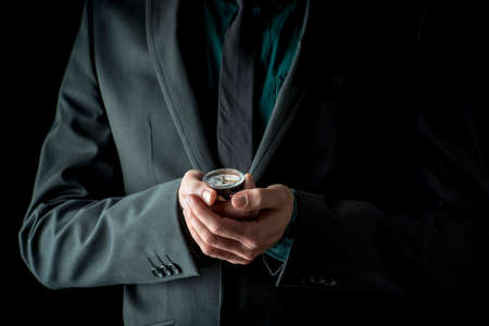 Businessman in suit holding compass in his hands, isolated on black background.の写真素材