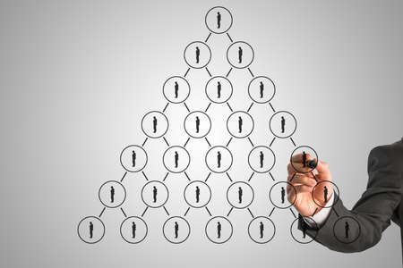 Businessman drawing a hierarchy concept on a virtual interface with a pyramid formation of business...