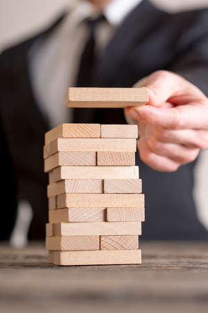 Businessman blurred in background stacking wooden bricks, building business concept.