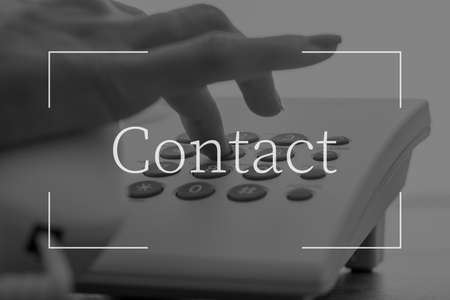 Contact text over female hand dialing a telephone number on white landline phone.の写真素材