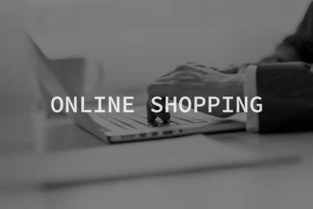 Online shopping text over hands of a businessman typing data on a laptop computer in greyscale image.の写真素材