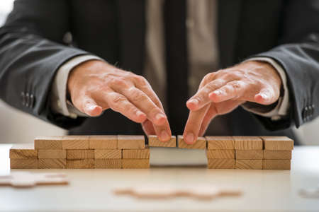 Businessman in suit assembling a bridge made from little blocks.の写真素材
