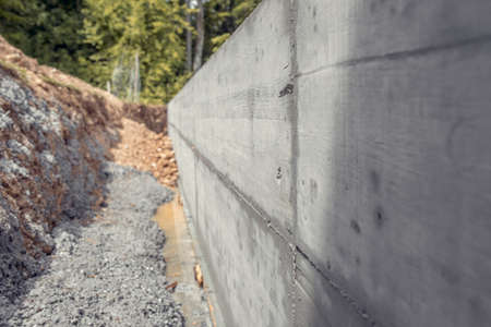 Dug out shaft next to a newly build concrete wall outside in a home garden to form a border between two properties.の写真素材