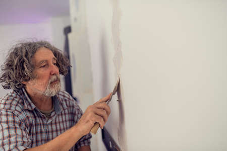 Retro effect faded and toned image of a builder plastering a wall as he repairs a crack or opening in a DIY and home renovation concept.の写真素材