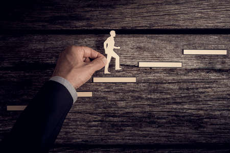 Retro style image of a successful businessman climbing the corporate ladder using paper cutouts.の写真素材