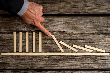 Businessman demonstrating stopping the domino effect using paper blocks.の写真素材