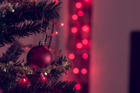 Retro image of festive Christmas background with red baubles and sparkling party lights over a shadowy background with copy space.の写真素材