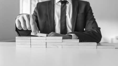 Man building staircase made of wooden pegs representing a way to success in greyscale image.の写真素材