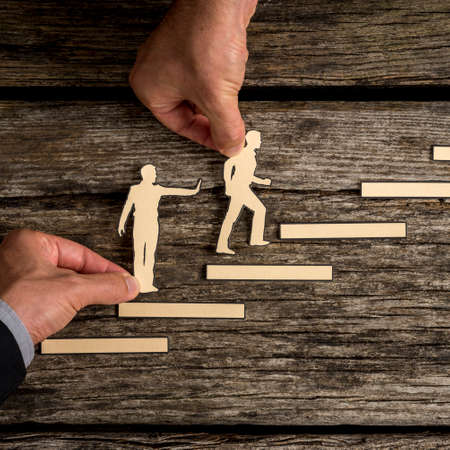 Business teamwork concept with the hands of two businesspeople supporting paper cut outs with one...