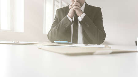 Thoughtful accountant sitting at his desk with paperwork and a calculator balancing his books.の写真素材