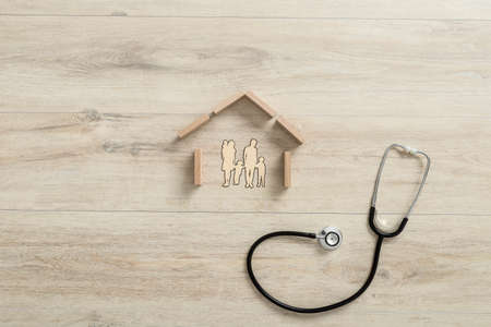 Conceptual of property insurance with the stethoscope next to the shape of a residential house made of building wooden blocks for a family with three children.の写真素材