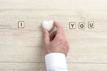 I Love You Valentines message with the hand of a man placing a small white heart to represent Love...