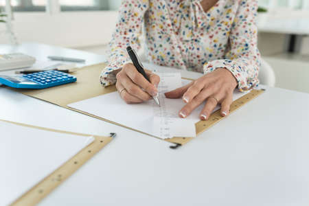 Accountant summing up the numbers writing on a printout receipt while making financial report.の写真素材