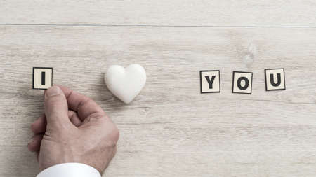 I Love You message with the hand of a man placing a letter to represent Love on a wooden background.の写真素材