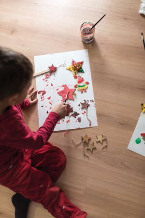 Young boy making decorations sitting on the floor painting or doing handicrafts, top view.の写真素材