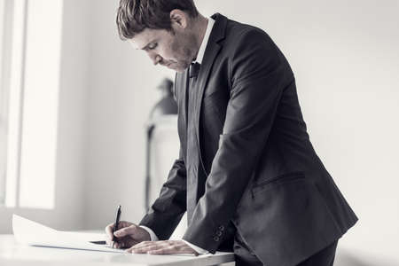 Side view of a designer or draftsman using ruler and pencil while working at the plan of a difficult project in the office, toned retro effect.の写真素材
