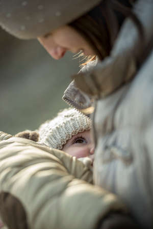 Outdoor portrait of mother breastfeeding her small baby wearing winter clothingの写真素材