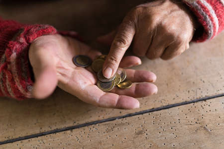 Hands of person in old sweater counting small change in palm of old hand.の写真素材