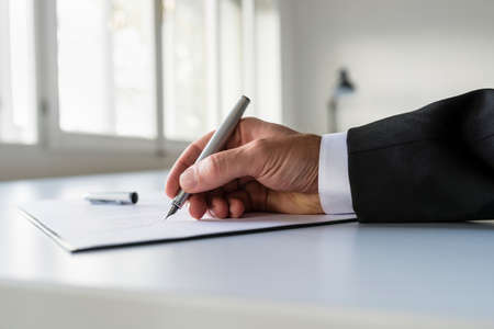 Low view of businessman hand signing business contract on white office desk.の写真素材