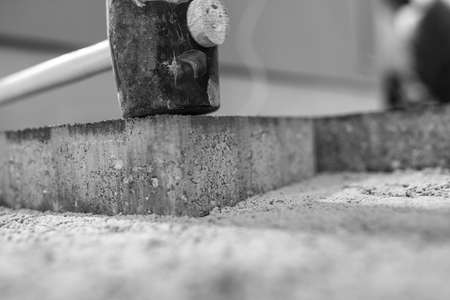 Greyscale image of new paving stones being installed outdoors showing the sand foundation and mallet.の写真素材
