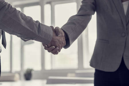 Retro toned image of male and female business partners shaking hands in agreement.の写真素材