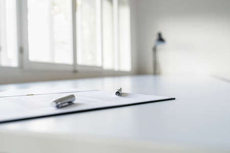 Ink pen lying on a contract right next to a signature in a bright office.