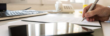 Businessman signing contract in a wide panorama view with a tablet computer with sunlight...