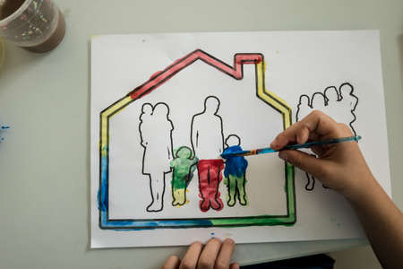 Top view of a boy painting a picture of a family in a house with colourful water colour paints.の写真素材