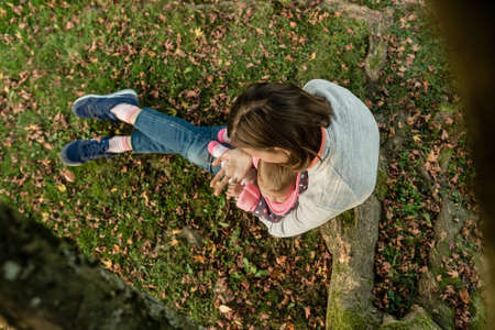 High-angle view of a young mother holding her cute baby girl while sitting outdoors in the park in the Autumn.の写真素材