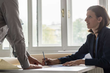 Two architects discussing document at a desk in the office.