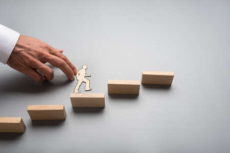 Businessman climbing up the steps to success and advancement in a conceptual image with paper...