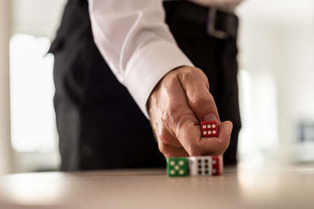Business challenge and risk concept - businessman throwing red dice over an office desk.
