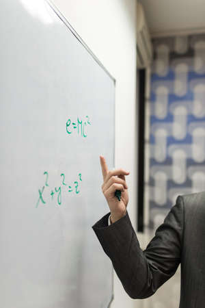 Closeup of professor pointing to a mass energy equivalence formula written on a white board.の写真素材