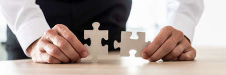 Wide view image of businessman holding two matching puzzle pieces. Conceptual of business vision and solution.の写真素材
