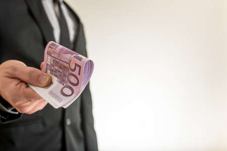 Businessman offering you five hundred Euro bills with plenty of copy space on the right side of an...