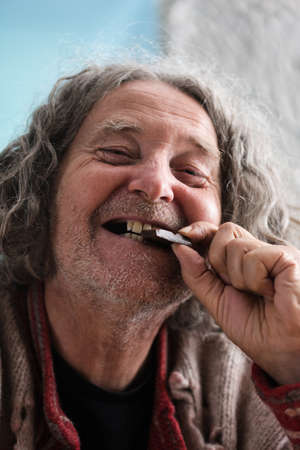 Happy senior man with missing teeth smiling as he bites in to a piece of chocolate.