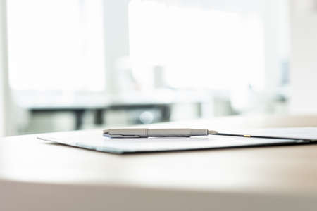 Low angle view of ink pen lying on document or contract on office desk.