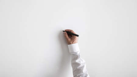 Male hand writing on white background with black marker. With plenty of copy space.の写真素材