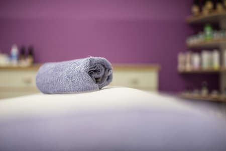 Rolled blue towel on a massage desk in a cosmetics salon in a conceptual image.の写真素材