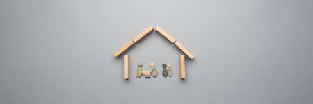 Wide view image of family made of pebbles inside a house made of wooden pegs over grey background.の写真素材