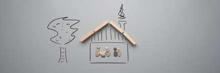 Family vision of a safe home in a conceptual image with family made of pebbles in a handdrawn house with wooden roof and a tree next to it.の写真素材