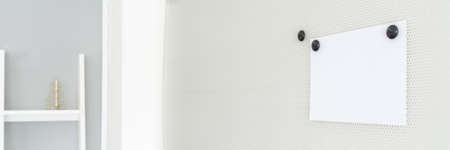 Wide view image of blank white paper placed with magnets on a magnetic board in an office.の写真素材