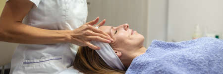 Young brunette enjoying herself as she is getting a rejuvenating face massage and skincare.