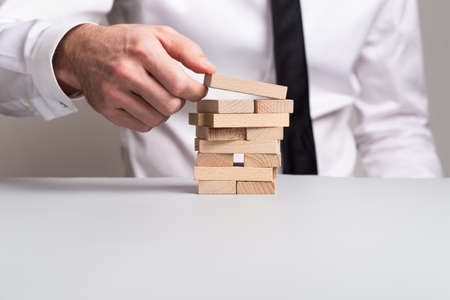 Front view of businessman building a tower of wooden pegs in a conceptual image of business vision.の写真素材