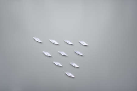 Ten paper origami boats positioned in a pyramid shape over grey background with copy space.の写真素材