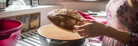 Woman standing in a home kitchen holding a freshly baked home made bread.