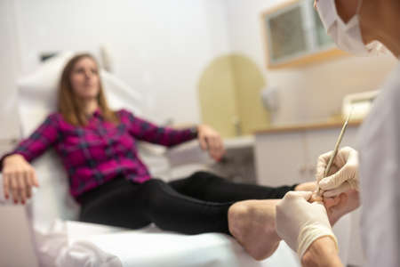 Closeup of professional pedicurist removing cuticle from toenails with stainless steel toll.の写真素材