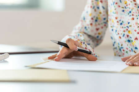 Low angle view of businesswoman at her office desk proofreading a document or contract in a paper folder before signing it.の写真素材